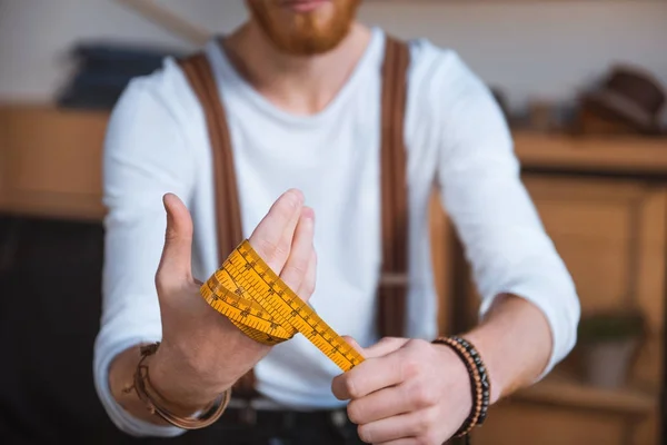 Vue rapprochée du jeune créateur de mode masculin tenant ruban à mesurer — Photo de stock