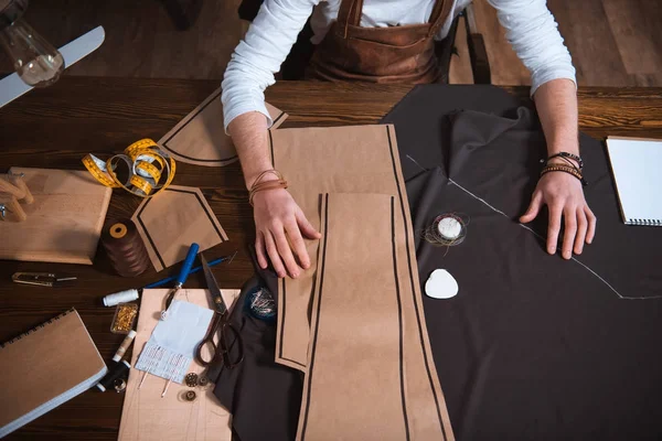 Tiro recortado de designer de moda masculina trabalhando com padrões de costura, ferramentas e tecido no local de trabalho — Fotografia de Stock