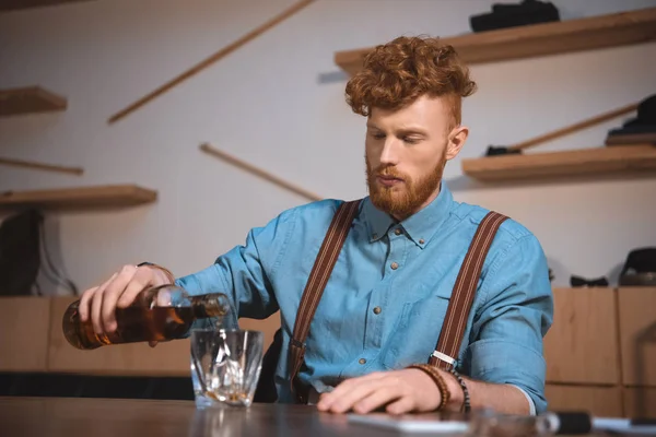 Guapo elegante joven verter whisky de botella en vidrio - foto de stock