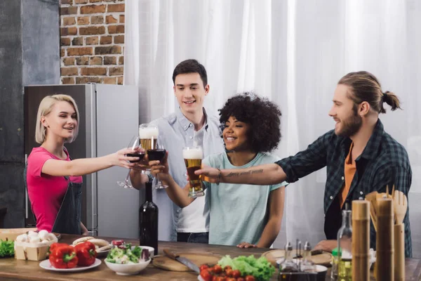 Amigos multiétnicos tintineo con copas de vino y cerveza - foto de stock
