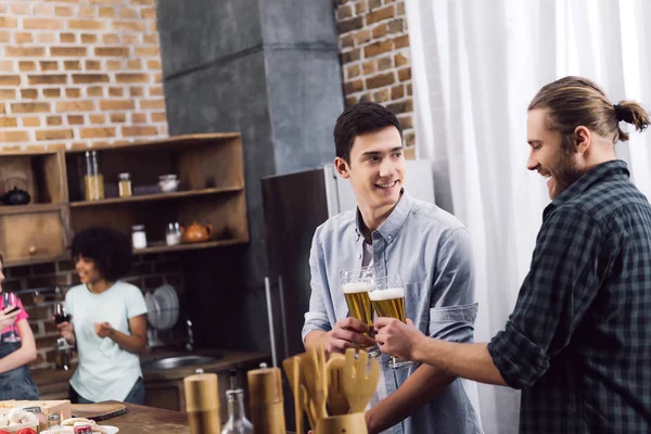 Мужчины звонят со стаканами пива на кухне — стоковое фото