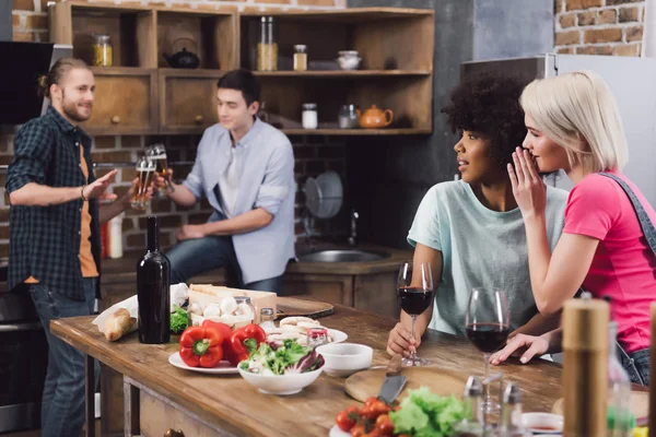 Filles multiethniques commérage sur les amis masculins dans la cuisine — Photo de stock