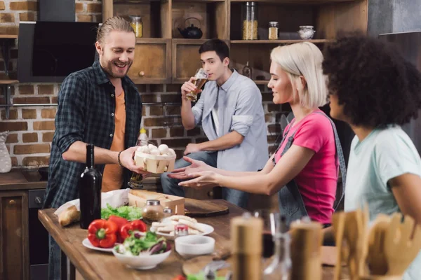 Man giving mushrooms to multiethnic friends who cooking — Stock Photo