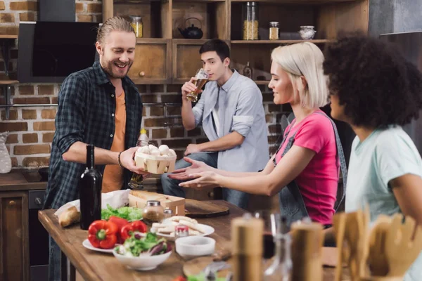 Homme donnant des champignons à des amis multiethniques qui cuisinent — Photo de stock