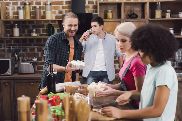 Amigos multiétnicos cocinando huevos de pollo y setas en la cocina - foto de stock