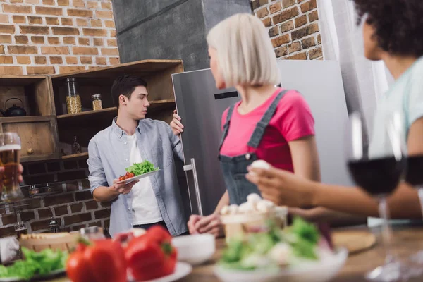 Человек берет овощи из холодильника на кухне — стоковое фото