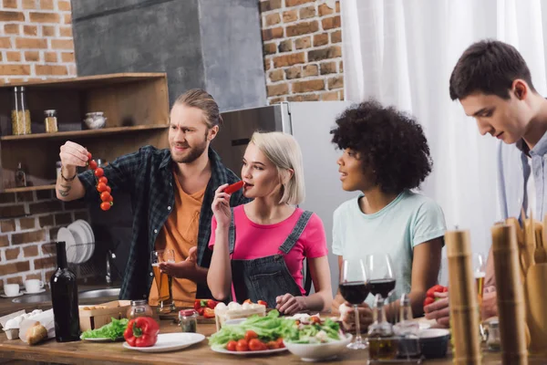 Multiethnic friends tasting some food while cooking in kitchen — Stock Photo