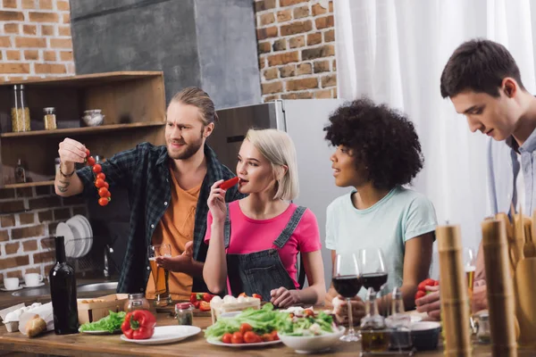 Amigos multiétnicos provar alguns alimentos enquanto cozinha na cozinha — Fotografia de Stock