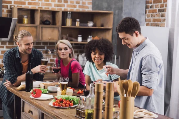 Amici multietnici cercando come uomo prendendo salsa fatta in casa con cucchiaio — Foto stock