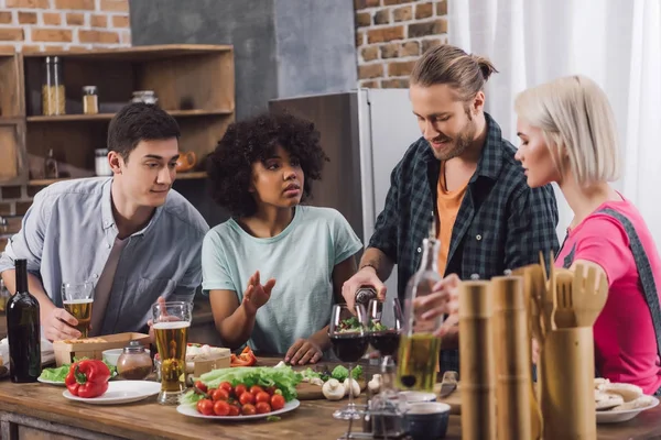 Man pouring alcohol to multiethnic friends glasses — Stock Photo