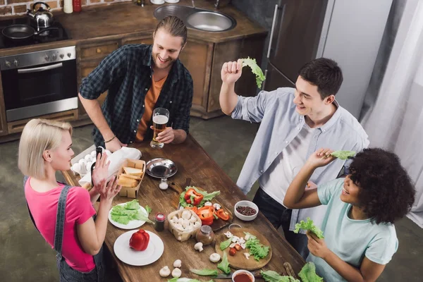 Vista aérea de amigos multiculturales jugando con hojas de ensalada - foto de stock