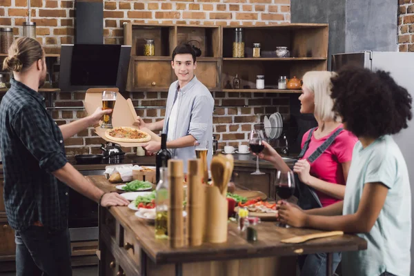 Homme montrant des amis multiethniques pizza maison — Photo de stock