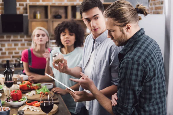 Amici multietnici alla ricerca di ricetta per il cibo con tablet — Foto stock