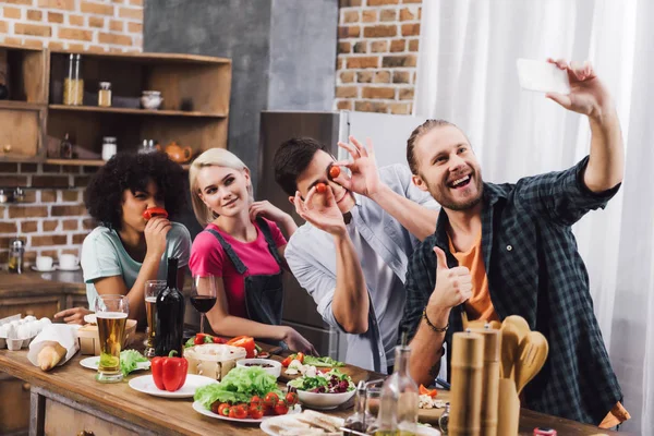 Amici multiculturali sorridenti scattare selfie con smartphone in cucina — Foto stock