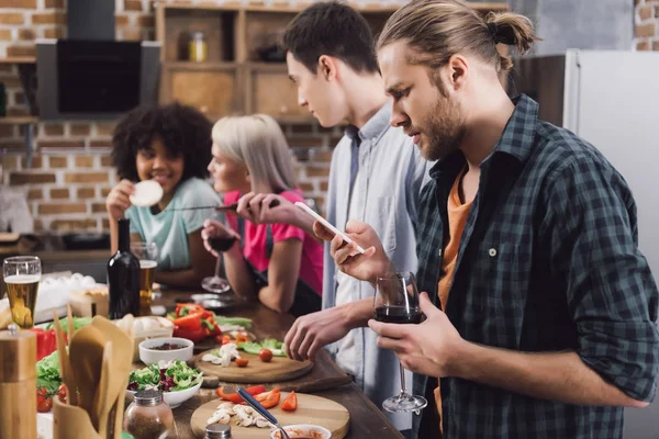 Mann schaut bei Party mit Freunden aufs Smartphone — Stockfoto