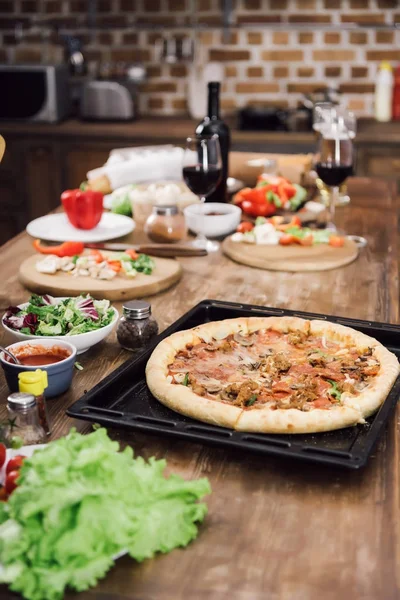Deliciosa pizza caseira na mesa na cozinha — Stock Photo
