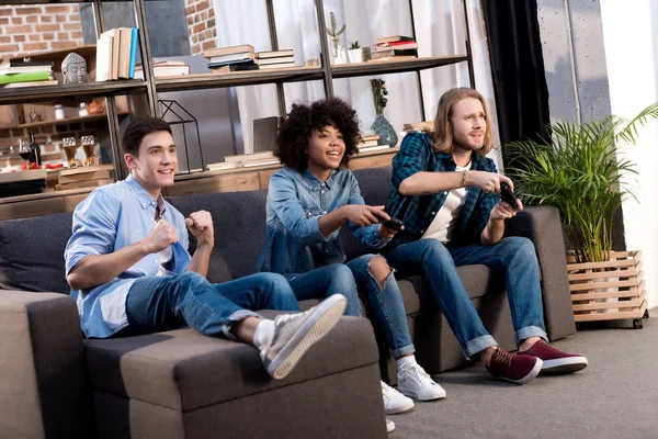 Amigos multiculturales jugando videojuegos en casa - foto de stock