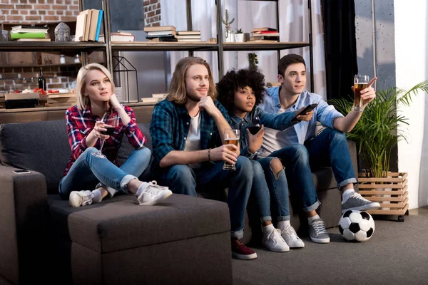 Multicultural friends watching soccer match and drinking alcohol at home — Stock Photo