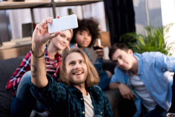 Multicultural friends taking selfie on sofa at home — Stock Photo