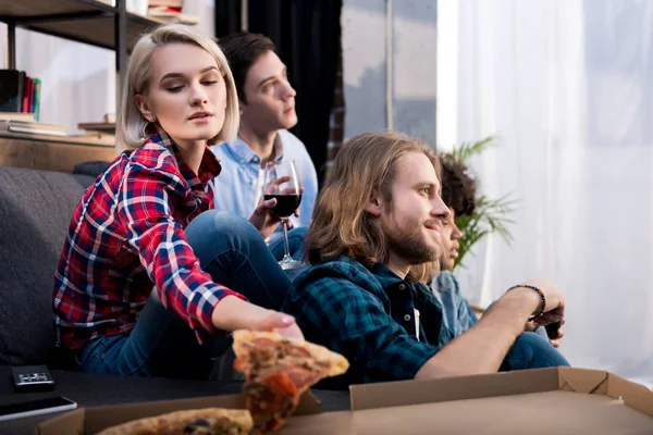 Chica tomando pedazo de pizza mientras pasar tiempo con amigos - foto de stock