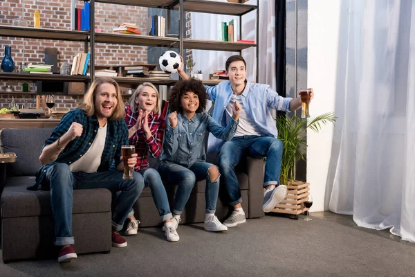 Amigos multiculturales viendo fútbol con cerveza en casa - foto de stock