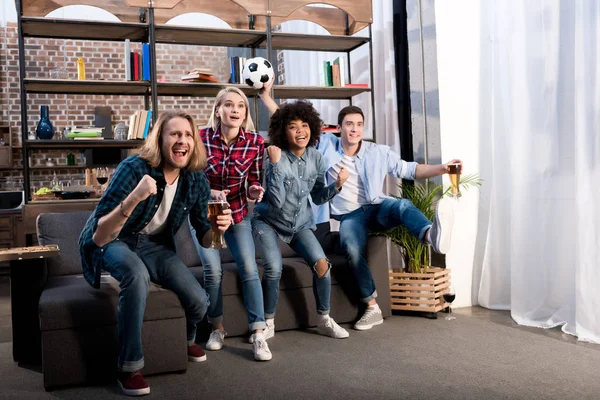 Multicultural friends watching football with beer at home — Stock Photo