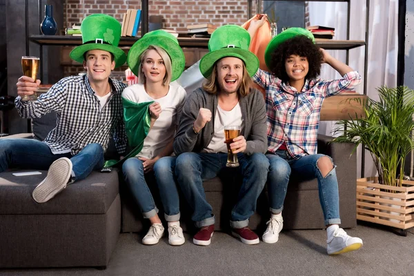 Amigos multiculturales viendo la televisión en día santo patrick - foto de stock