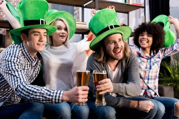 Amici multiculturali guardando la tv e occhiali tintinnanti, santo patrick day concept — Foto stock