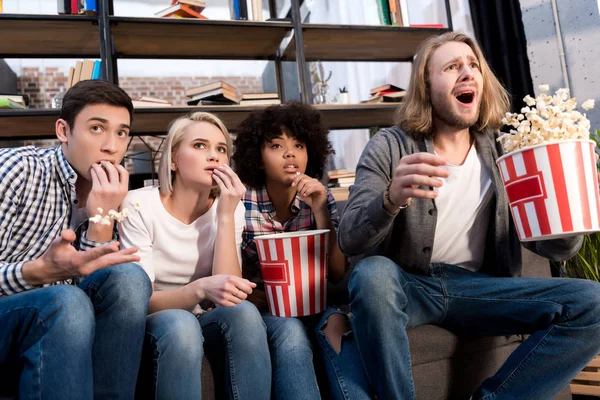 Amigos multiculturais chocados assistindo filme com pipocas — Fotografia de Stock