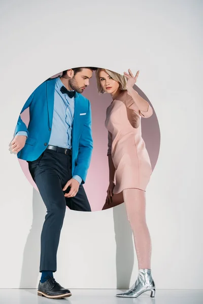 Fashionable couple in love stepping through hole on grey — Stock Photo