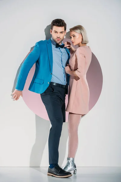 Fashionable young couple in love looking at camera while standing together in hole on grey — Stock Photo