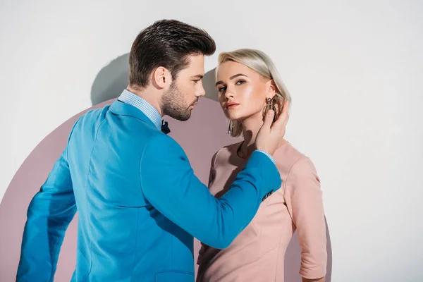 Beau jeune couple à la mode en amour posant ensemble dans le trou sur gris — Photo de stock