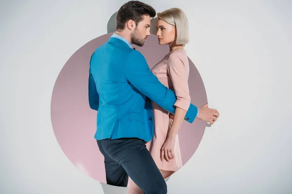 Beautiful stylish young couple looking at each other while standing on hole on grey — Stock Photo