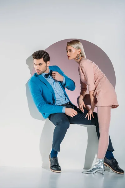 Beau jeune couple regardant loin tout en étant assis ensemble dans l'ouverture sur gris — Photo de stock