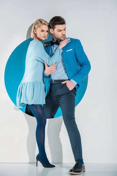 Giovane coppia alla moda che esce dal buco blu sul grigio — Foto stock