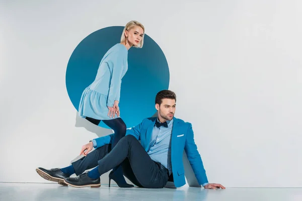 Beautiful stylish young couple posing near blue hole on grey — Stock Photo