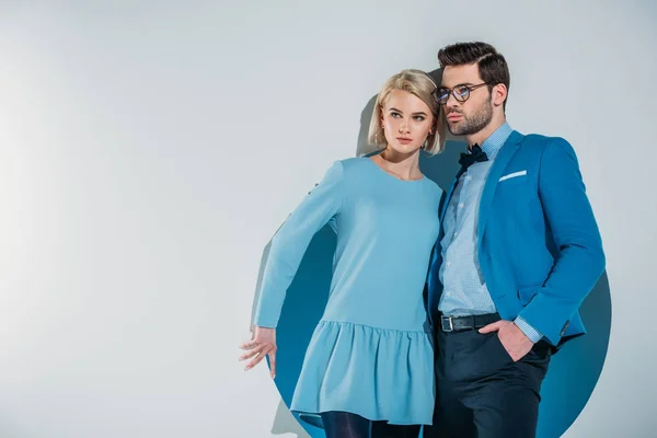 Fashionable young couple looking away while standing together in hole on grey — Stock Photo