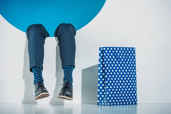 Vue partielle du jeune homme élégant avec sac à provisions tombant dans le trou sur gris — Photo de stock