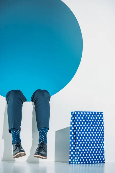 Cropped shot of young man with shopping bag falling into hole on grey — Stock Photo