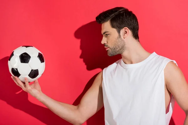 Bel giovane uomo che tiene il pallone da calcio sul rosa — Foto stock