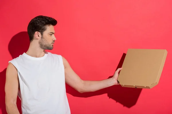 Handsome young man holding blank pizza box on pink — Stock Photo