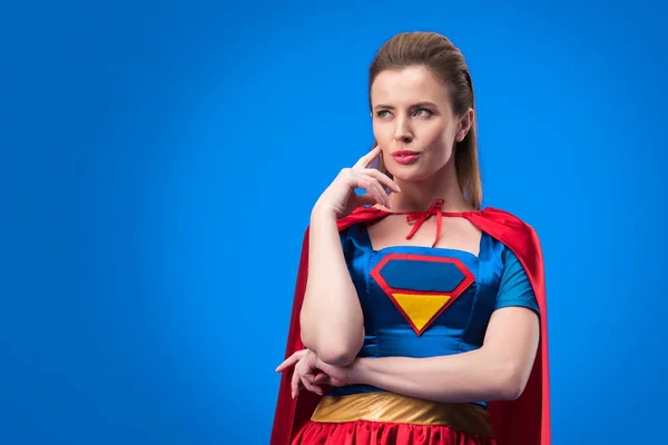 Porträt einer nachdenklichen Frau im Superheldenkostüm, die isoliert auf blauem Grund wegschaut — Stockfoto