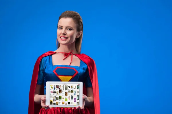 Портрет веселий жінка в костюмі супергероя показують, планшетному ізольовані на блакитному — стокове фото