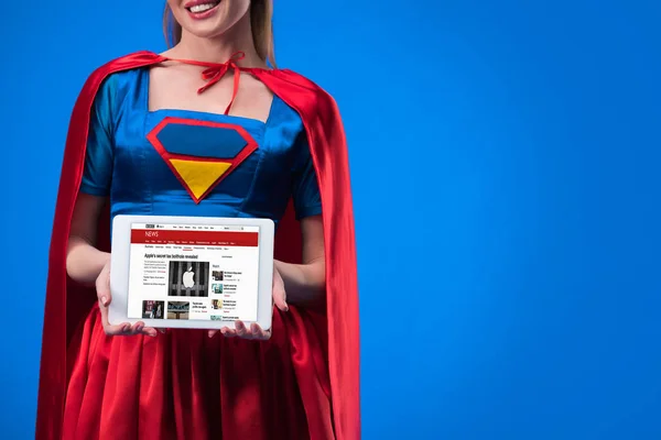 Schnappschuss einer Frau im Superheldenkostüm zeigt Tablet isoliert auf blauem Grund — Stockfoto