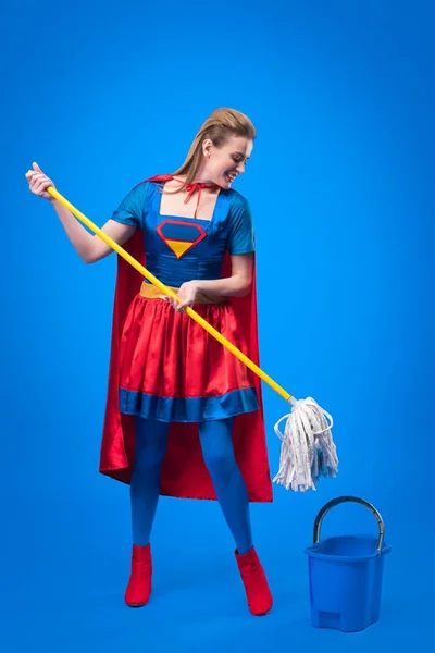 Femme en costume de super héros avec serpillière et seau pour le nettoyage isolé sur bleu — Photo de stock