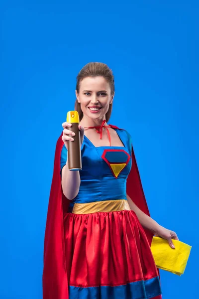 Retrato de bela super-mulher sorridente com pano e detergente para limpeza isolado em azul — Fotografia de Stock