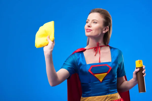 Retrato de hermosa supermujer con trapo y detergente para la limpieza aislada en azul - foto de stock