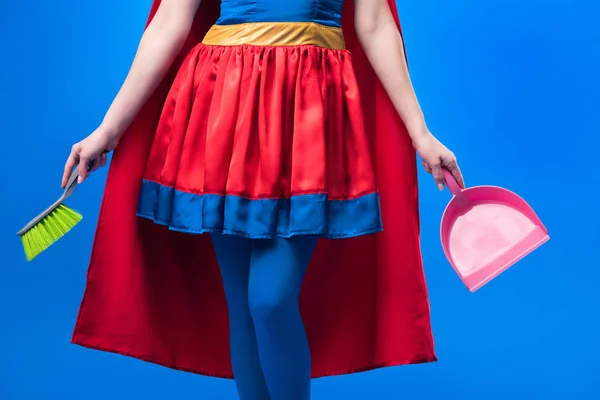Visão parcial da mulher em traje de super-herói com vassoura e colher para limpeza isolada em azul — Fotografia de Stock