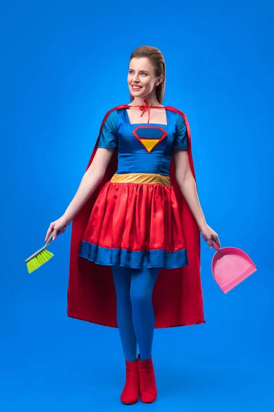 Mulher em traje de super-herói com vassoura e colher para limpeza isolada em azul — Fotografia de Stock