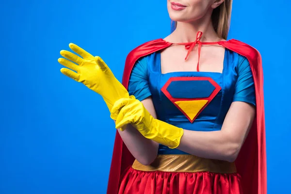 Corte tiro de mulher em traje de super-herói usando luvas de borracha isoladas em azul — Fotografia de Stock